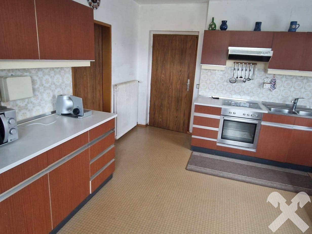 Funktionale Küche mit braunen Holzschränken, integriertem Backofen und Linoleumboden.