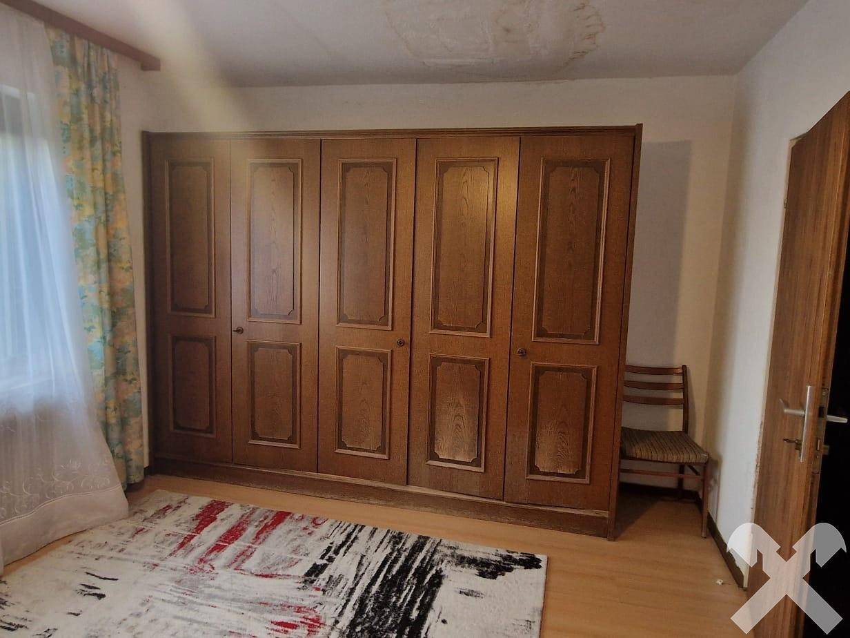 Schlafzimmer mit großem, traditionellem Holzschrank und hellem Laminatboden.