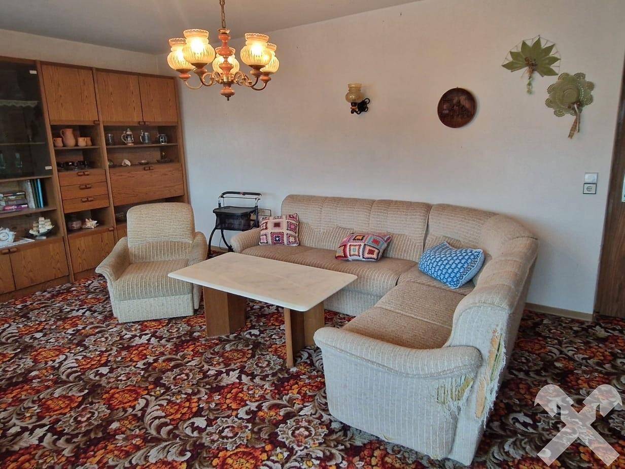 Geräumiges Wohnzimmer mit bequemer Sitzecke, traditionellem Teppich und Holzmöbeln.