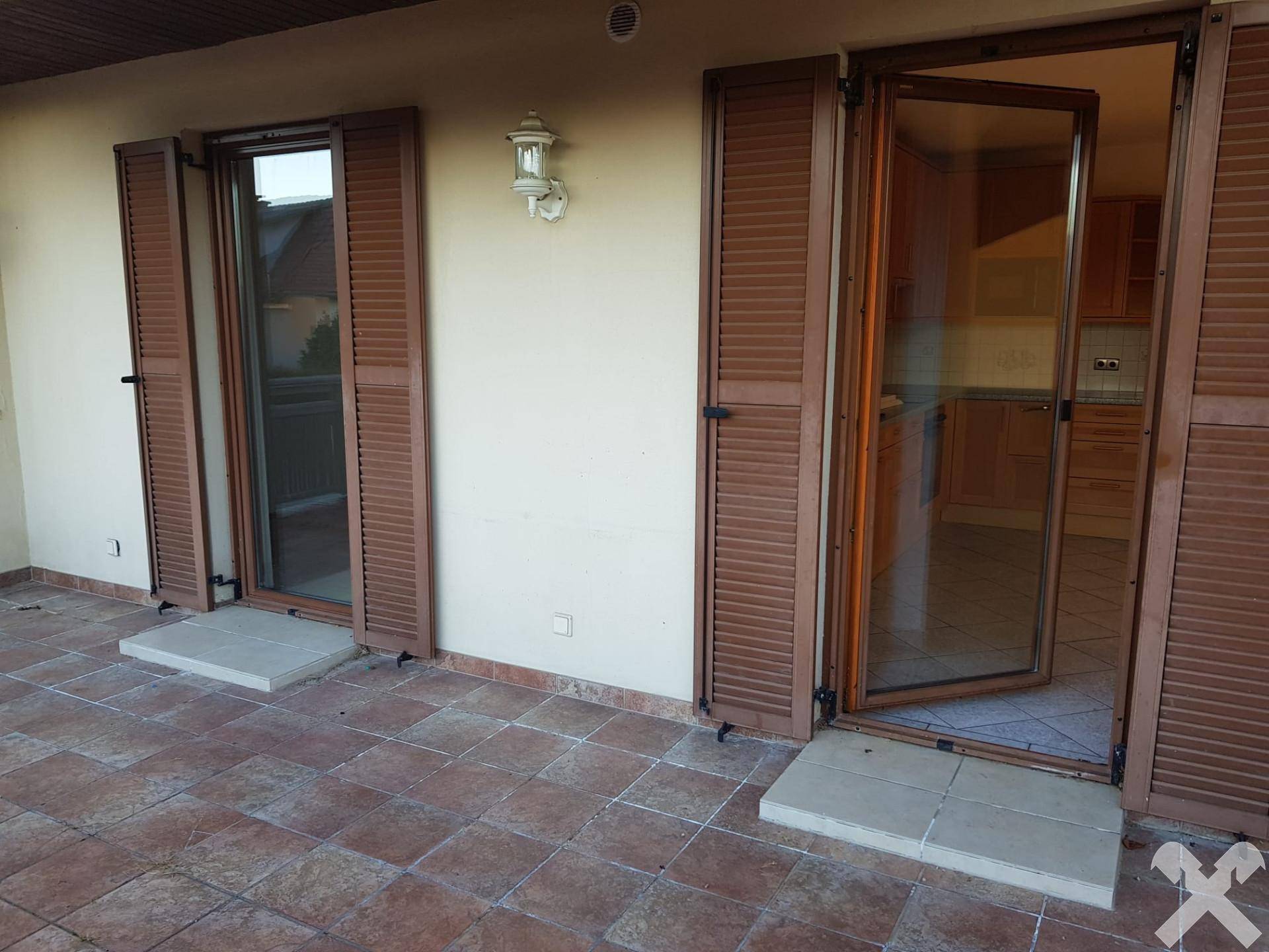 Geräumige, geflieste Terrasse mit Zugang zu den Innenräumen und Holzfensterläden.
