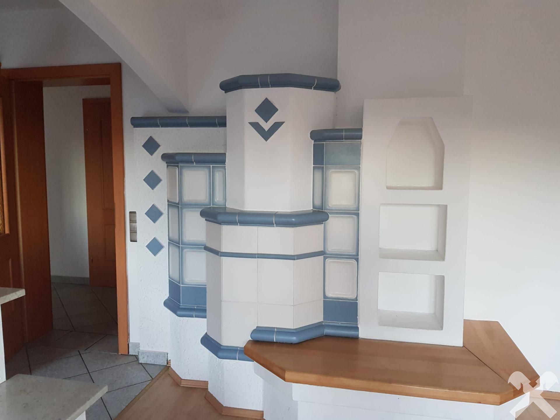 Traditioneller Kachelofen in Blau-Weiß mit integrierten Ablageflächen, ein Blickfang im Raum.