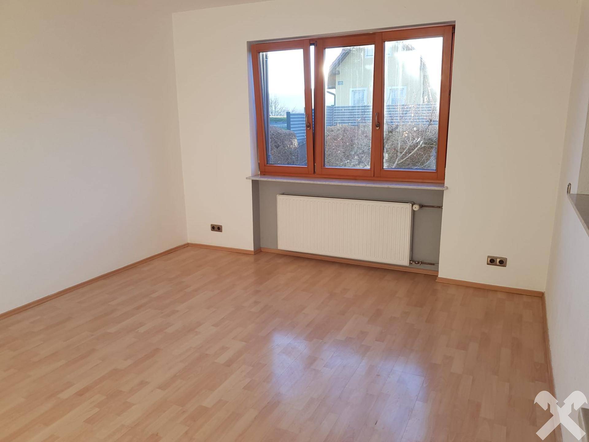 Heller, leerer Raum mit großem Fenster und Heizkörper, bereit zur individuellen Gestaltung.