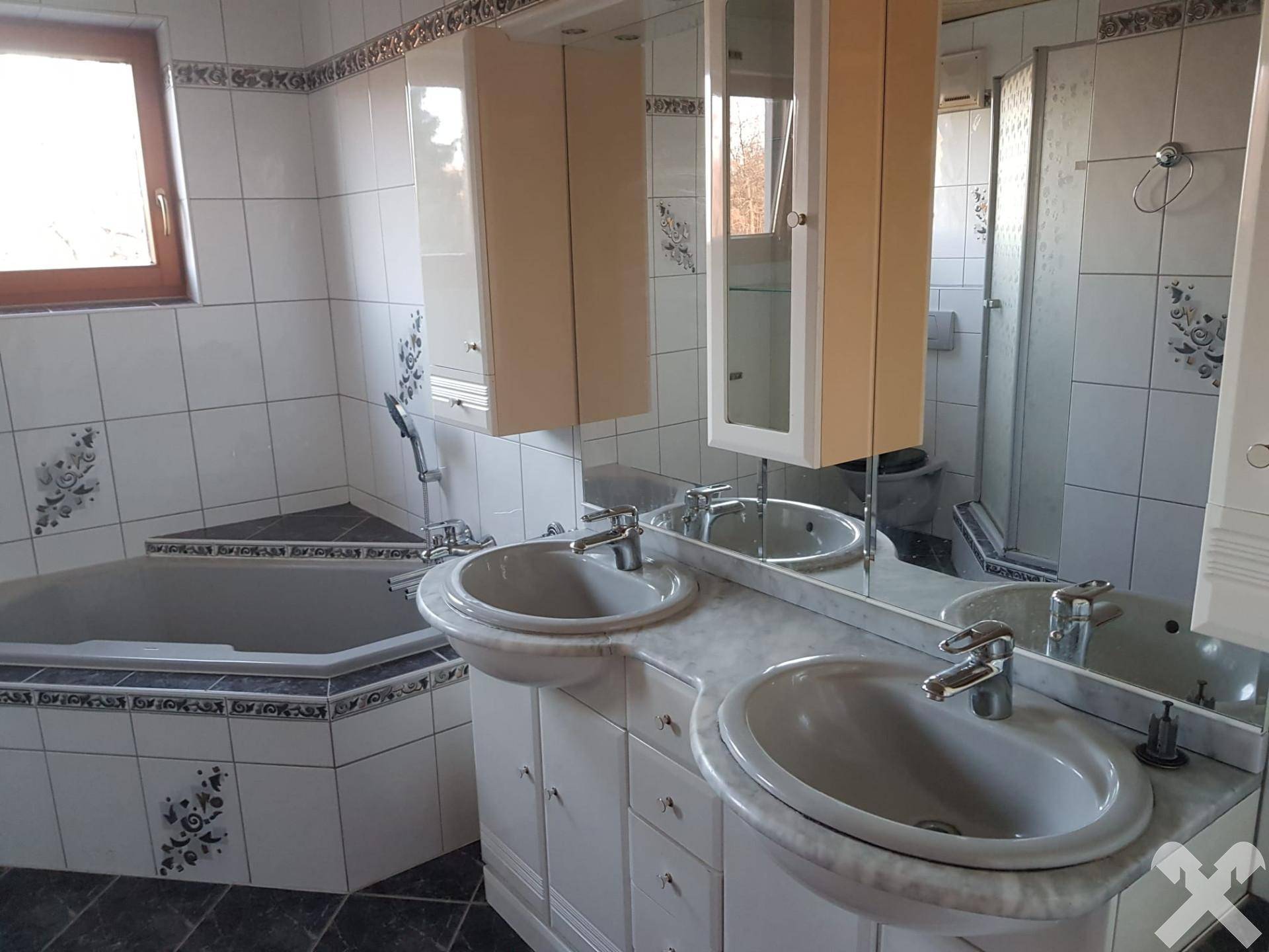 Geräumiges Badezimmer mit Doppelwaschbecken, Eckbadewanne und Spiegelschrank.
