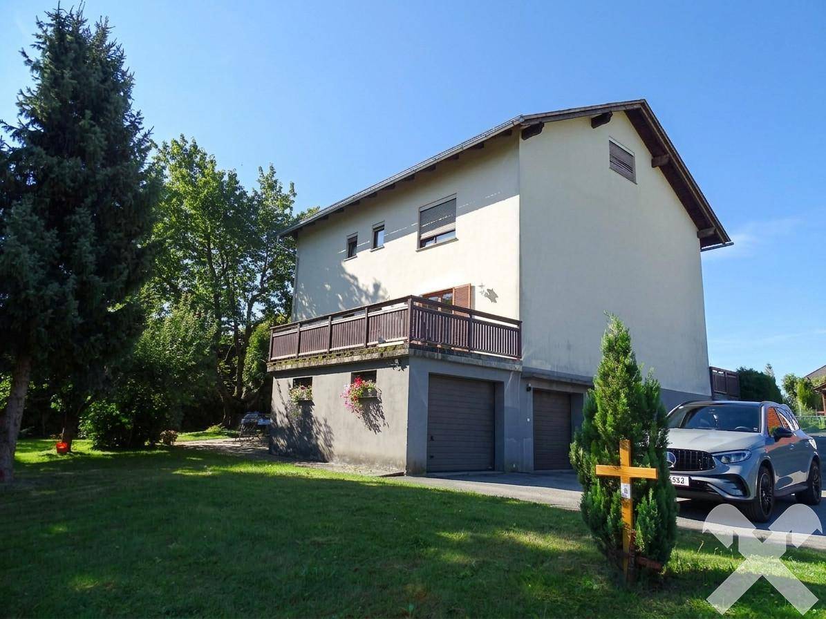 Ansicht des Hauses von der Seite mit Doppelgarage, Balkon und gepflegtem Vorgarten.