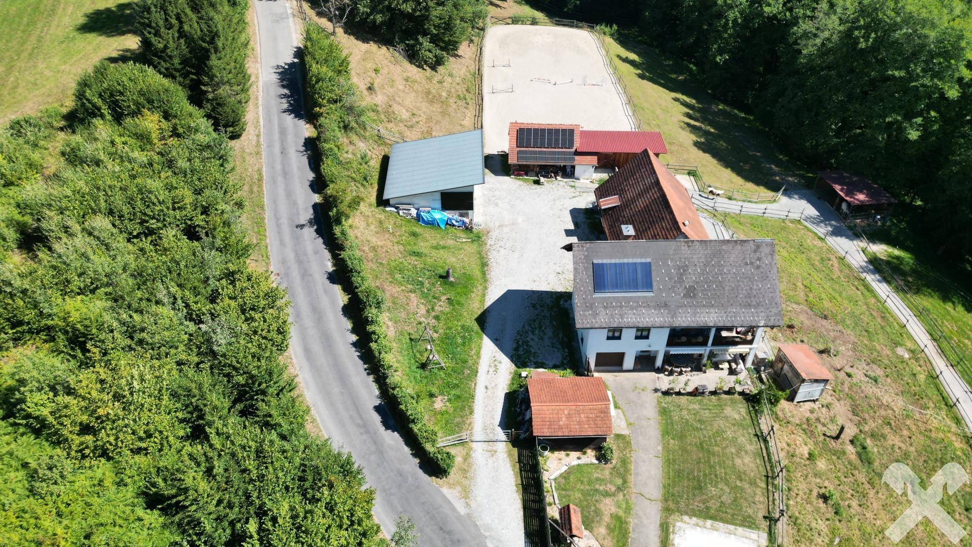Übersicht des Anwesens aus der Vogelperspektive mit Zufahrtsstraße, Reitplatz und Waldrand.