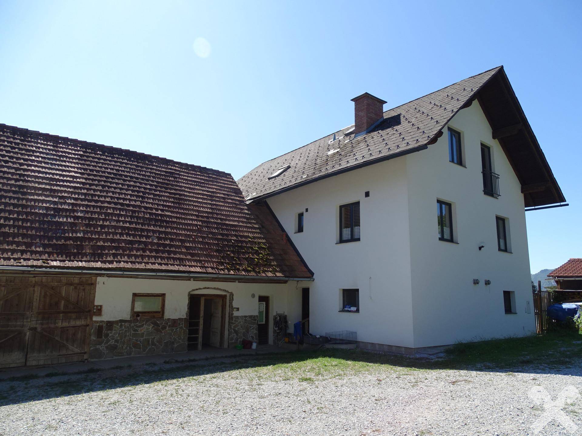Seitenansicht des Wohnhauses mit angebauter Scheune und großem Schotterplatz davor.