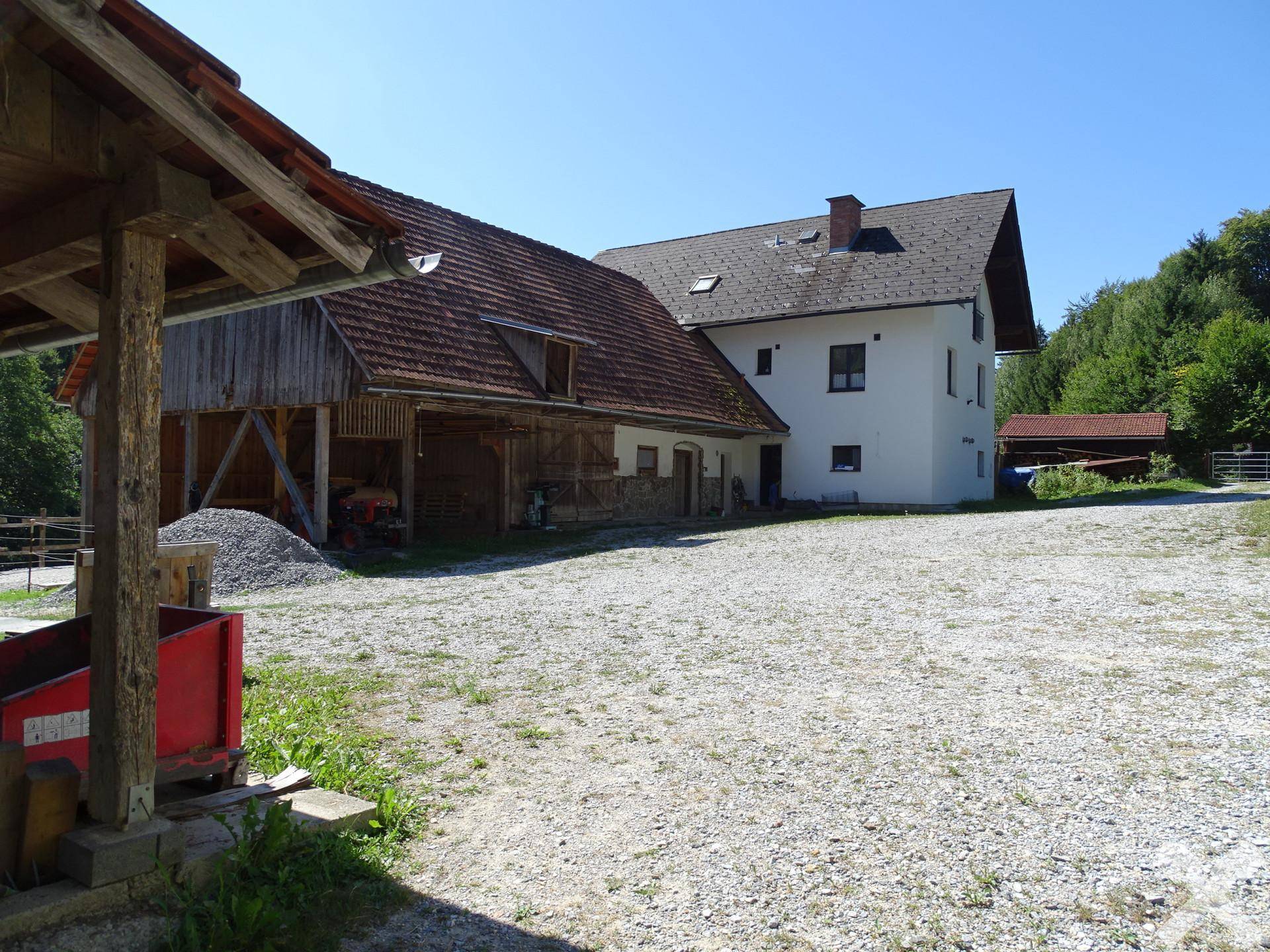Wohnhaus und angrenzende Scheune mit großem Schotterplatz und Blick auf die Umgebung.