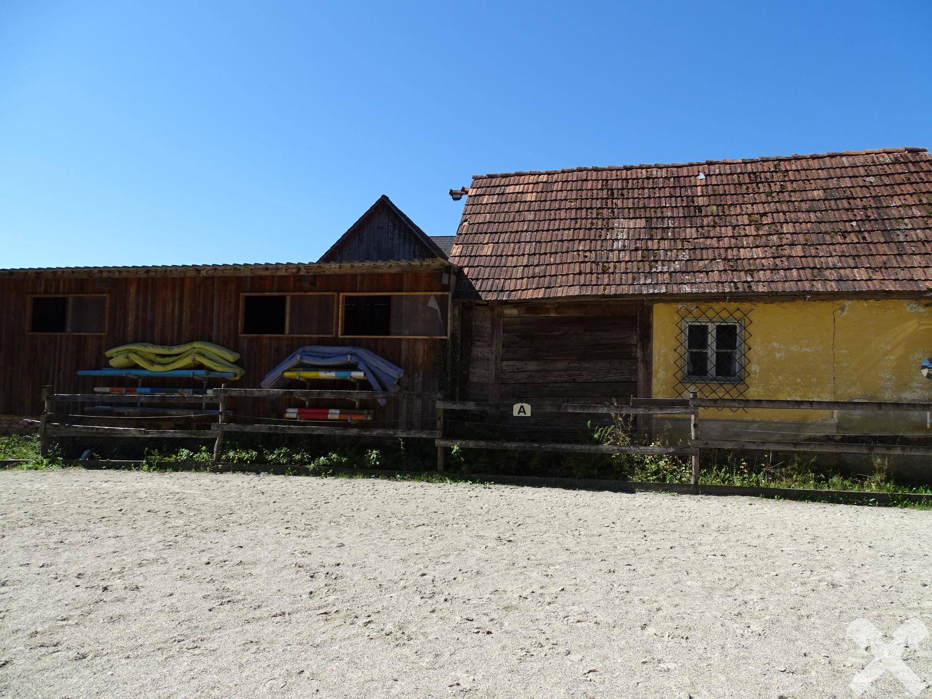 Rustikale Holzgebäude neben dem Reitplatz, genutzt für Lagerung von Reitzubehör.