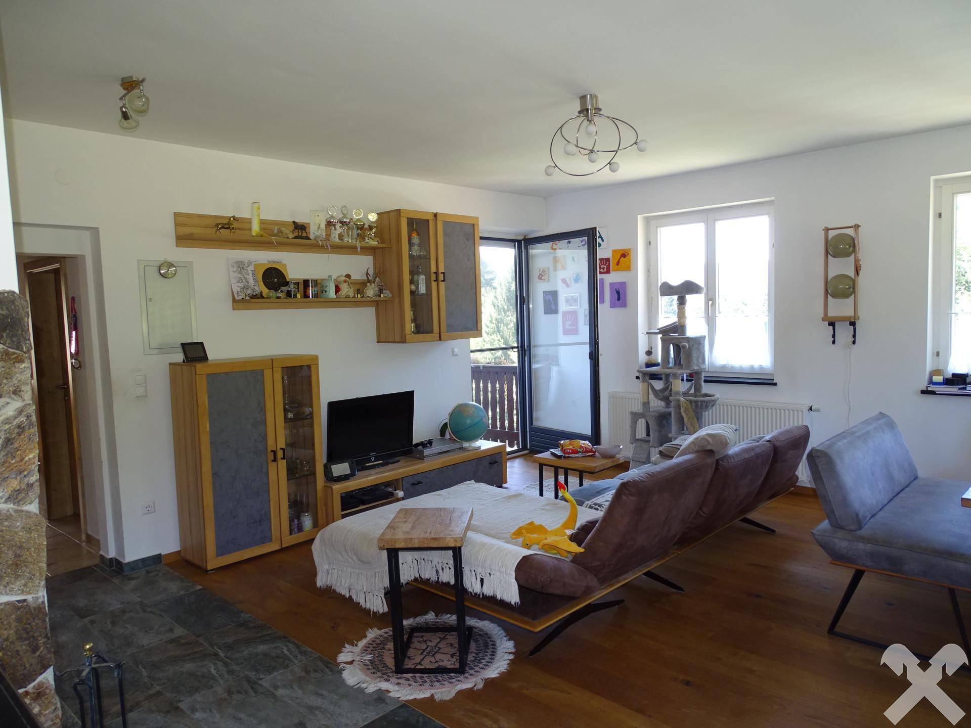 Heller Wohnbereich mit Sofa, TV-Möbeln und Zugang zu einem Balkon.