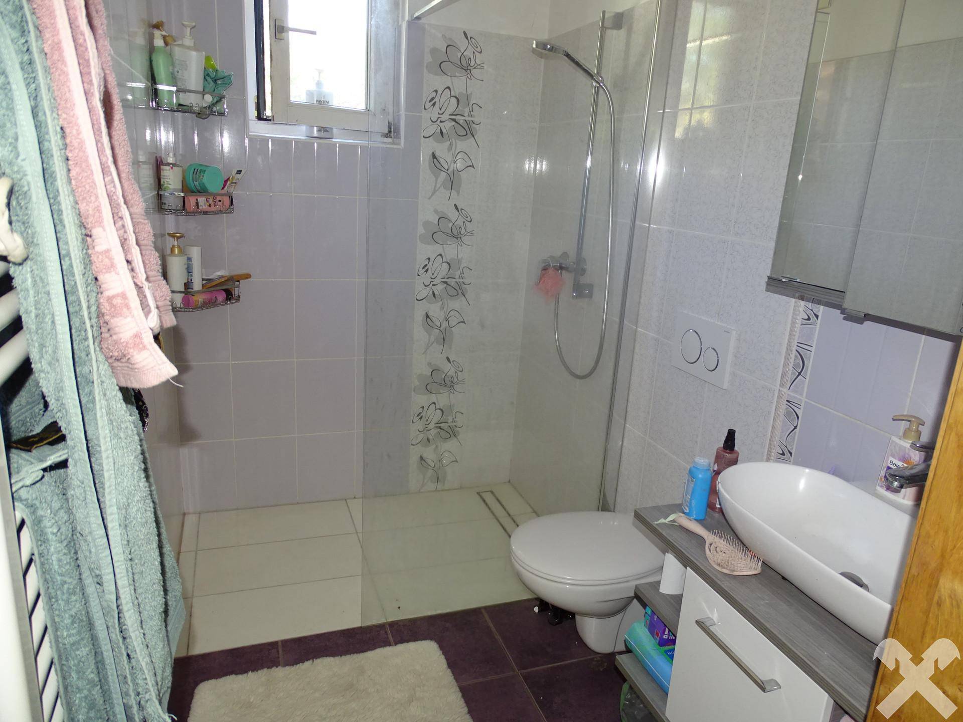 Badezimmer mit Dusche, WC und Waschbecken, ausgestattet mit hellen Fliesen.