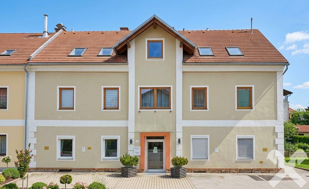 Symmetrische Fassade des Gebäudes mit mehreren Fenstern und Dachgauben unter blauem Himmel.