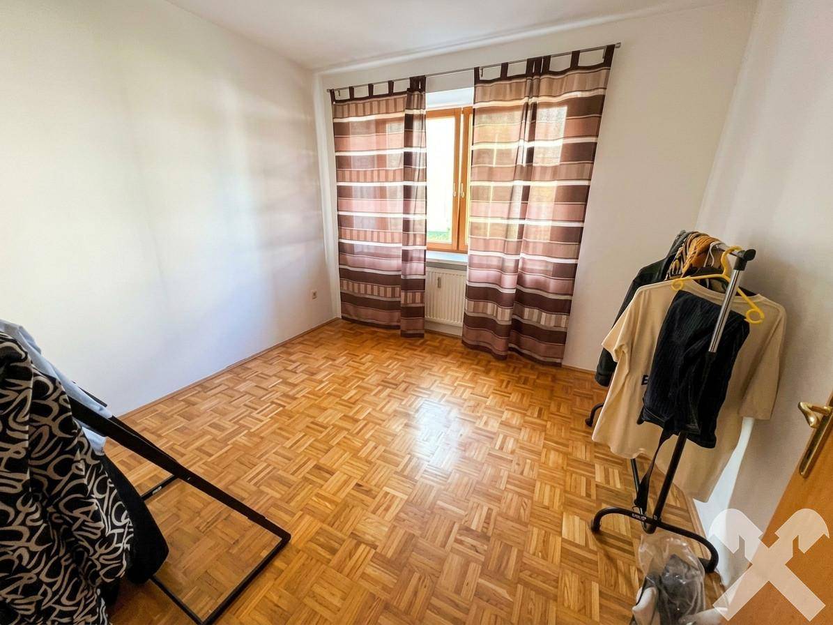 Schlafzimmer mit Parkettboden und Fenster, bereit zur individuellen Einrichtung.
