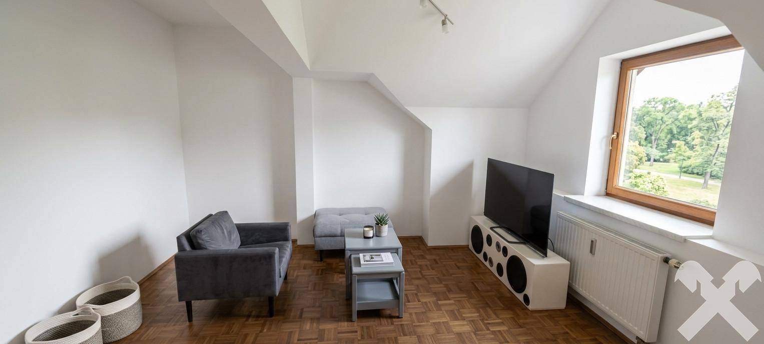 Helles Wohnzimmer im Dachgeschoss mit Schrägdach, Parkettboden und Blick ins Grüne.