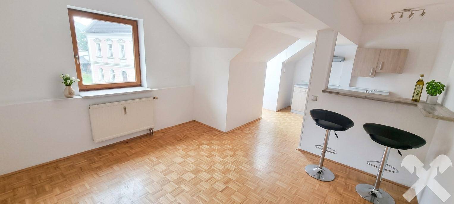 Heller Wohnbereich im Dachgeschoss mit Bar und Parkettboden, einladend und funktional.