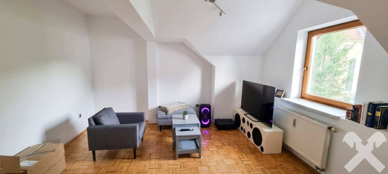 Gemütliches Wohnzimmer mit Sofa, Fernseher und Dachschrägen, ideal zum Entspannen.