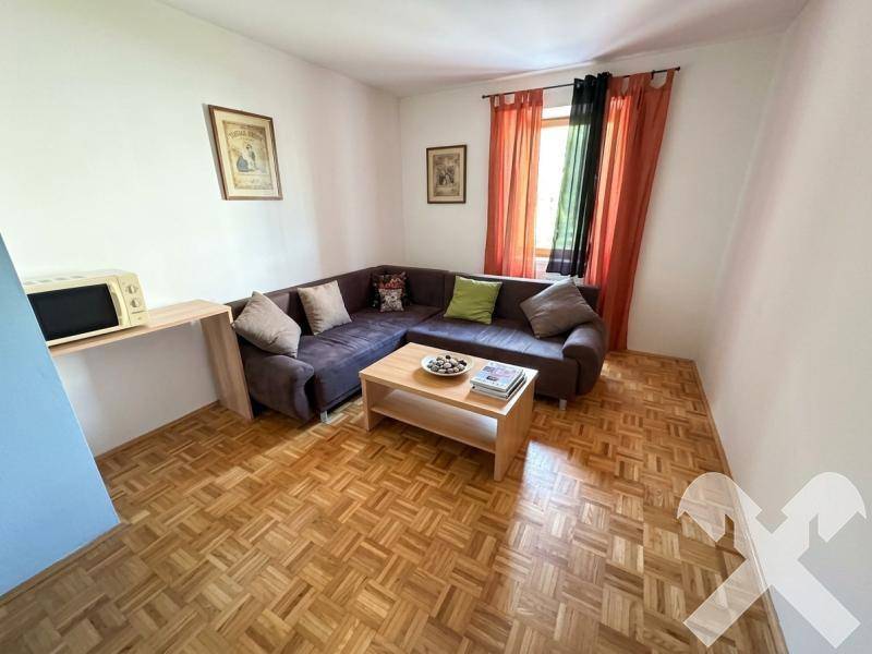 Gemütliches Wohnzimmer mit Ecksofa, Couchtisch und Parkettboden, ideal zum Entspannen.