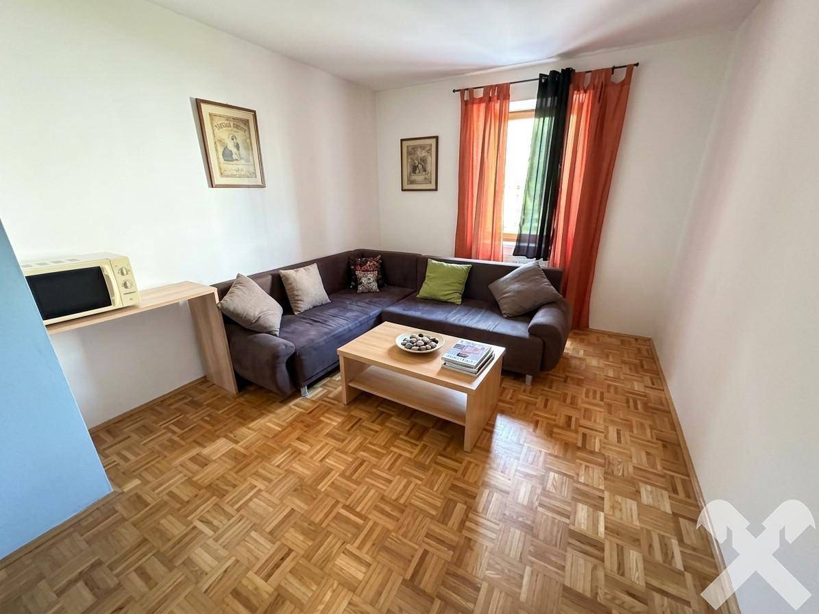 Gemütliches Wohnzimmer mit braunem Ecksofa, Holztisch und Parkettboden.