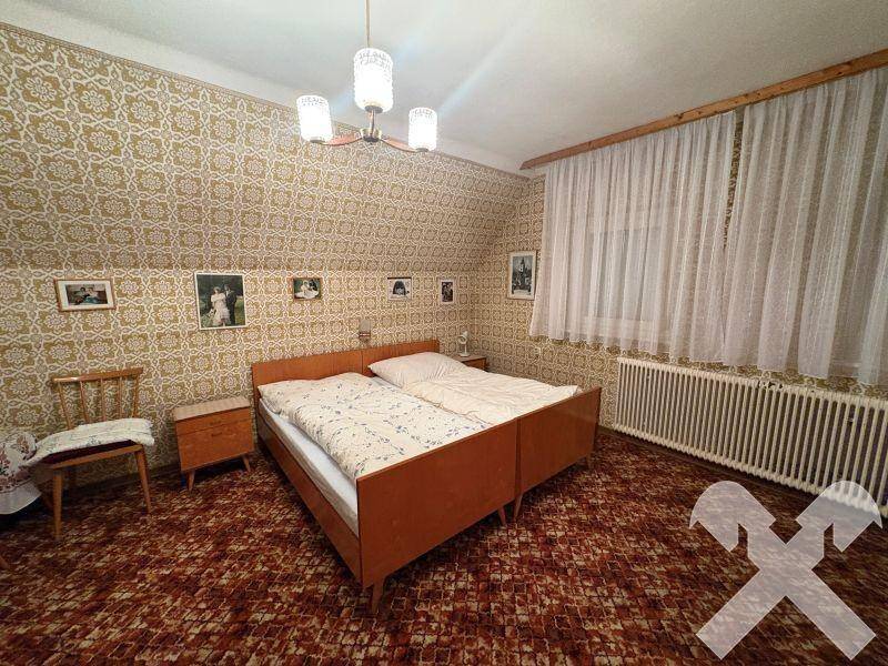 Schlafzimmer mit gemusterter Tapete, Doppelbett und Teppichboden, ausgestattet mit einem Heizkörper.
