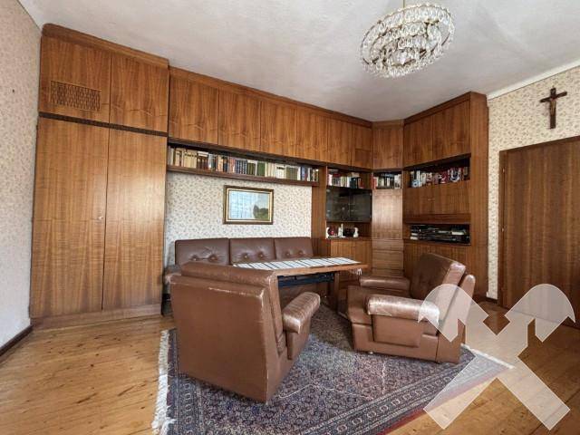 Wohnzimmer mit großen Holzschränken, Ledersesseln und einem traditionellen Teppich.