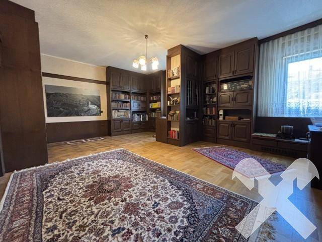 Klassisches Arbeitszimmer mit umfangreichen Holzregalen, Parkettboden und traditionellem Teppich.