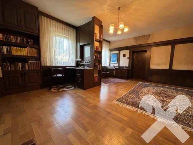Geräumiges Arbeitszimmer mit Holzboden, Einbauschränken und Schreibtischbereich.