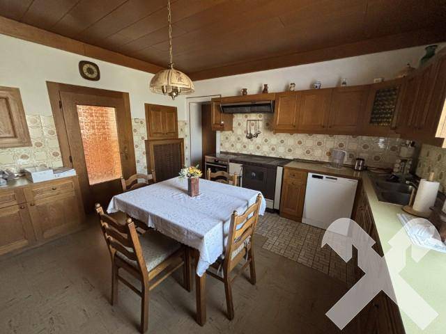 Traditionelle Küche mit Holzeinbauten, Essbereich und karierten Fliesen an der Wand.
