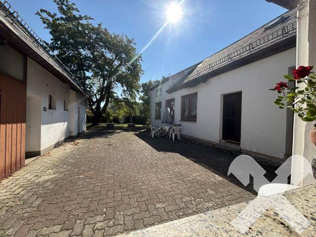 Gepflasterter Hofbereich zwischen Gebäuden mit Sitzgelegenheiten und viel Sonnenlicht.