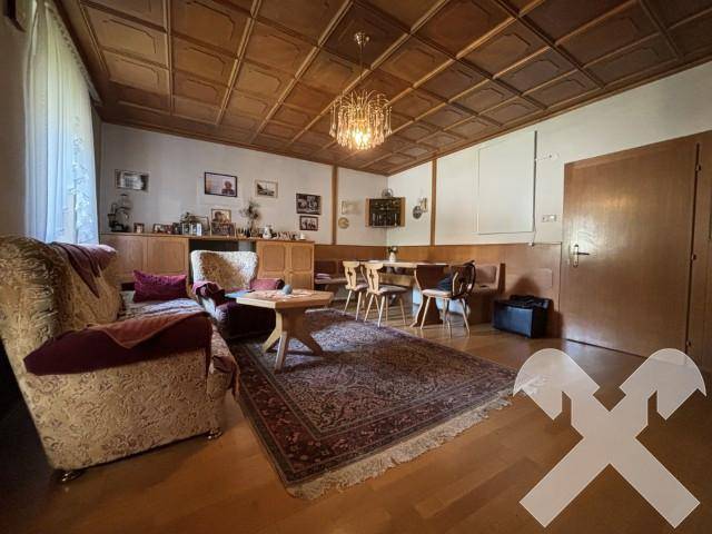 Gemütliches Wohnzimmer mit Holzboden, Kassettendecke und traditionellen Möbeln.