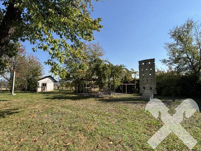 Großer Gartenbereich mit Schuppen, Bäumen und einer dekorativen Steinsäule.