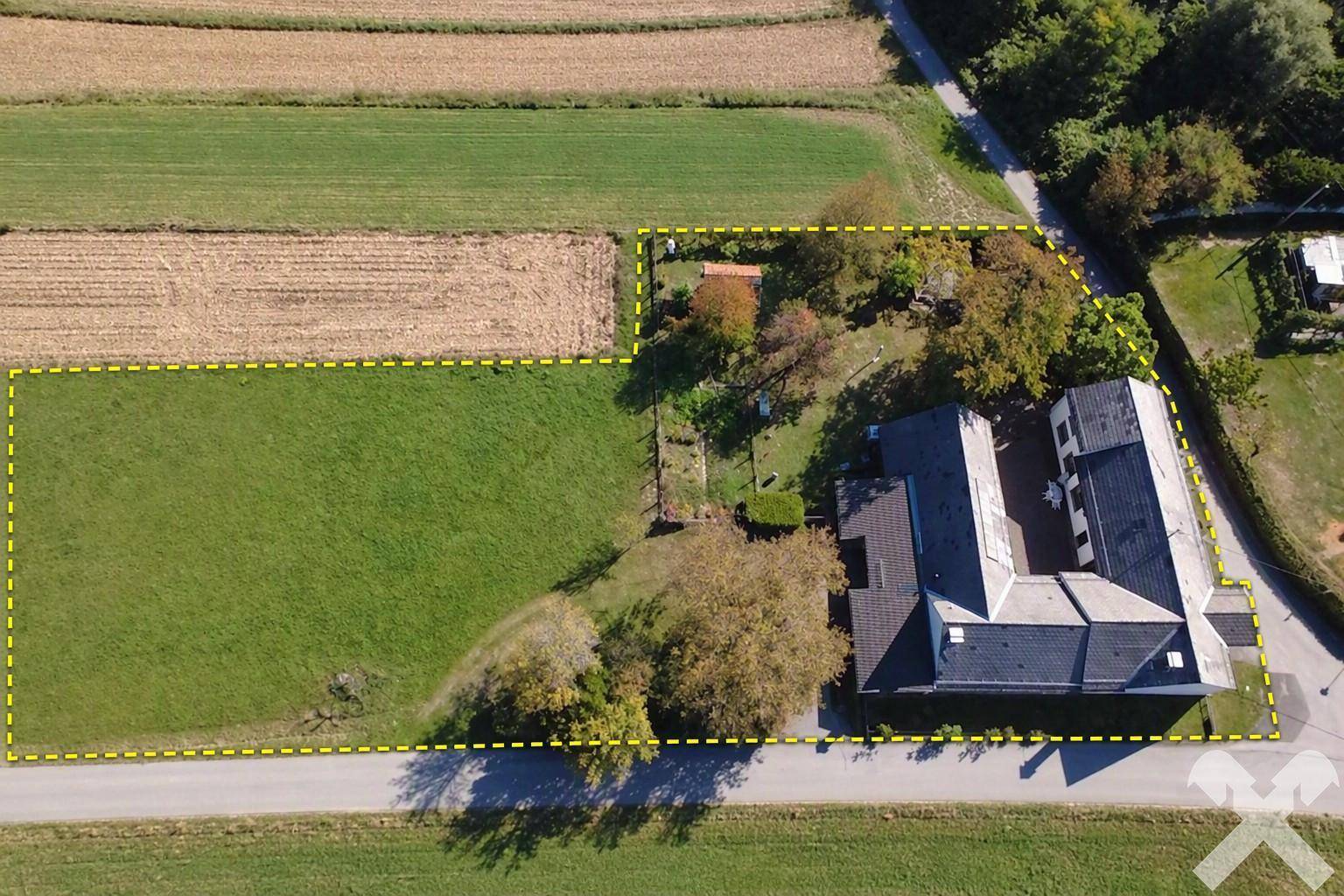 Luftaufnahme eines Hauses mit großem Grundstück, umgeben von Feldern und grüner Landschaft.