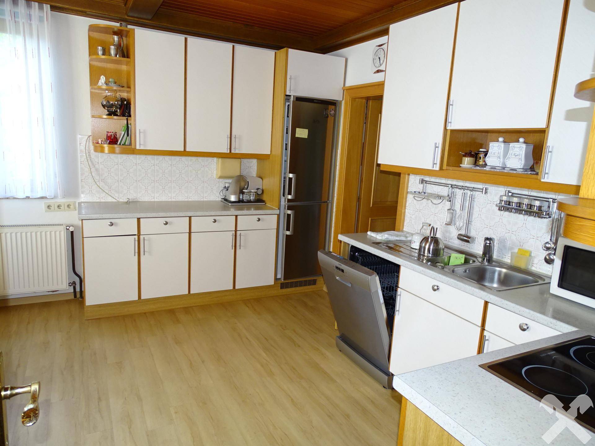 Küche mit weißen Schränken, integriertem Geschirrspüler und Holzdecke, bietet viel Stauraum.