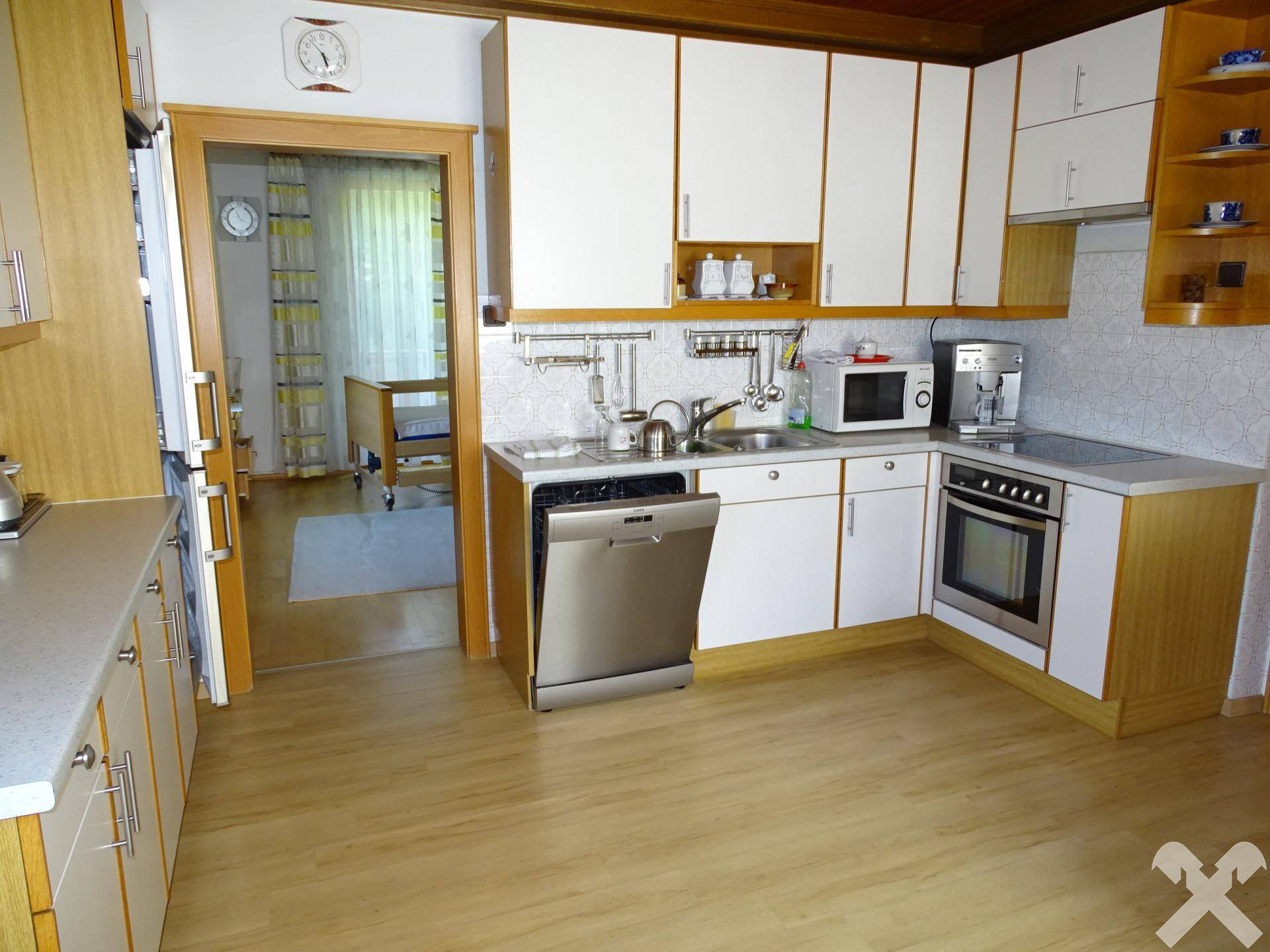 Funktionale Küche mit weißen Fronten, Backofen, Geschirrspüler und Kaffeemaschine, gut ausgestattet.