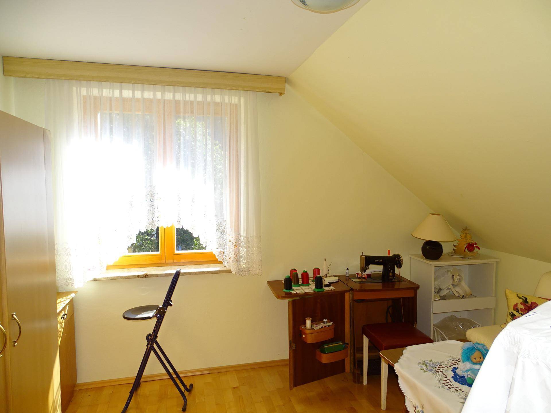 Helles Arbeitszimmer mit Nähmaschine und Fenster, unter einer Dachschräge gelegen, ideal für Hobbys.