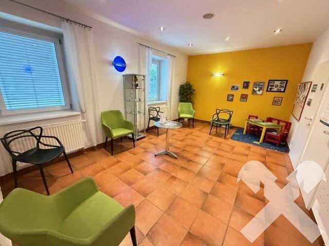 Geräumiges Wartezimmer mit farbenfrohen Akzenten, bequemen Sitzgelegenheiten und einer Spielecke für Kinder.