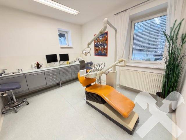 Helles Behandlungszimmer mit moderner zahnmedizinischer Ausrüstung und einem großen Fenster für Tageslicht.