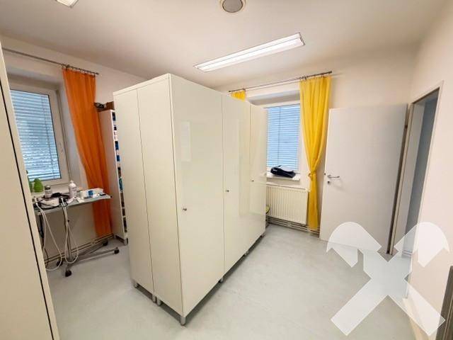 Geräumiger Lagerraum oder Büro mit großen weißen Schränken und Fenstern mit farbigen Vorhängen.