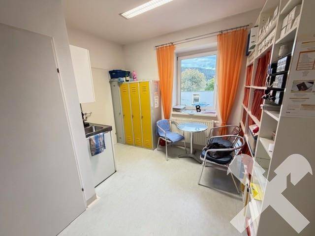 Personalraum mit Küchenzeile, gelben Spinden und einem Fenster mit Blick ins Grüne.