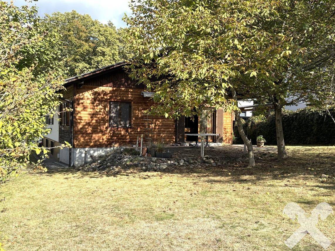Haus mit großem Garten und altem Baumbestand, umgeben von üppiger Natur.