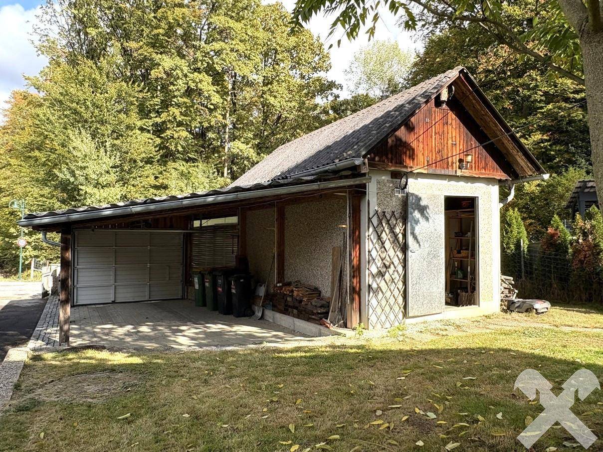 Separate Garage mit Carport und Abstellraum, umgeben von Grünflächen.