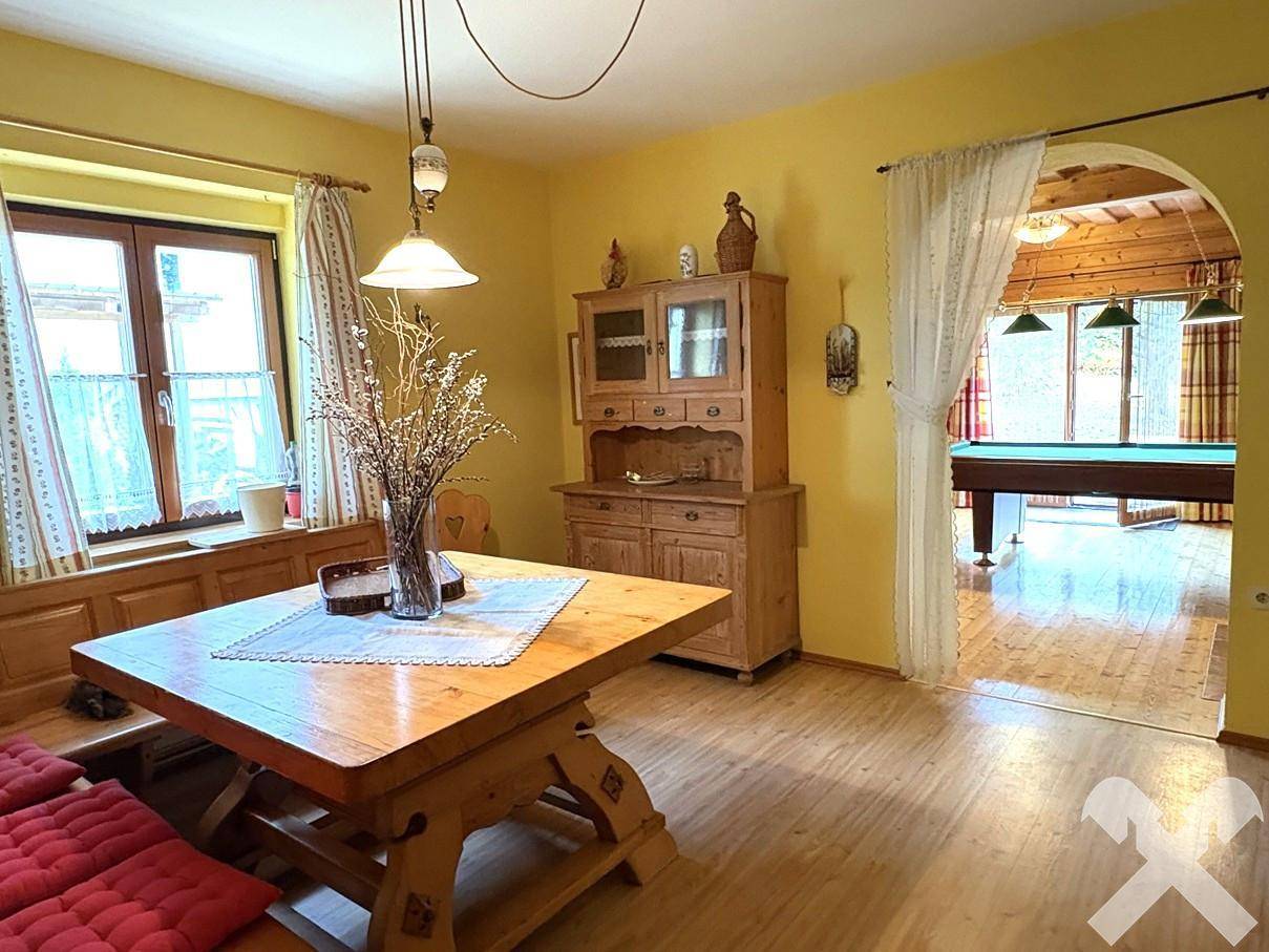 Rustikaler Essbereich mit Holztisch und Schrank, offen zum Wohnzimmer.
