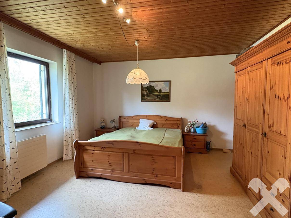 Schlafzimmer mit Holzbett und Kleiderschrank, sowie einer Holzdecke.