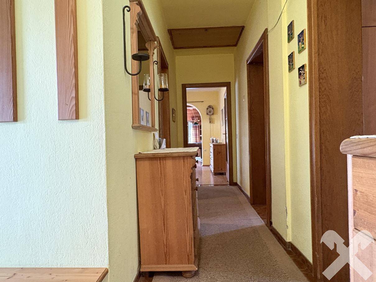 Heller Flur mit gelben Wänden und Holzmöbeln, führt zu weiteren Räumen.