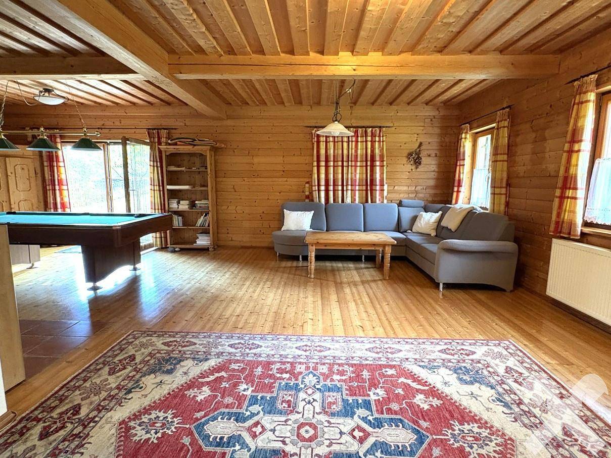 Großzügiges Wohnzimmer mit Billardtisch, Holzboden und Holzbalkendecke.