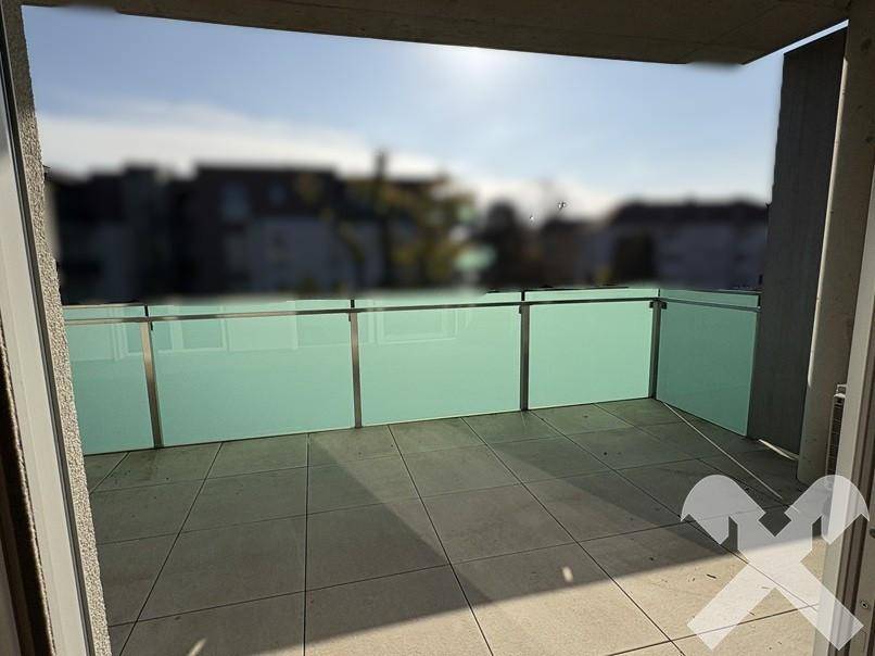 Geräumiger Balkon mit Fliesenboden und Glasgeländer, bietet einen schönen Ausblick und viel Sonnenlicht.