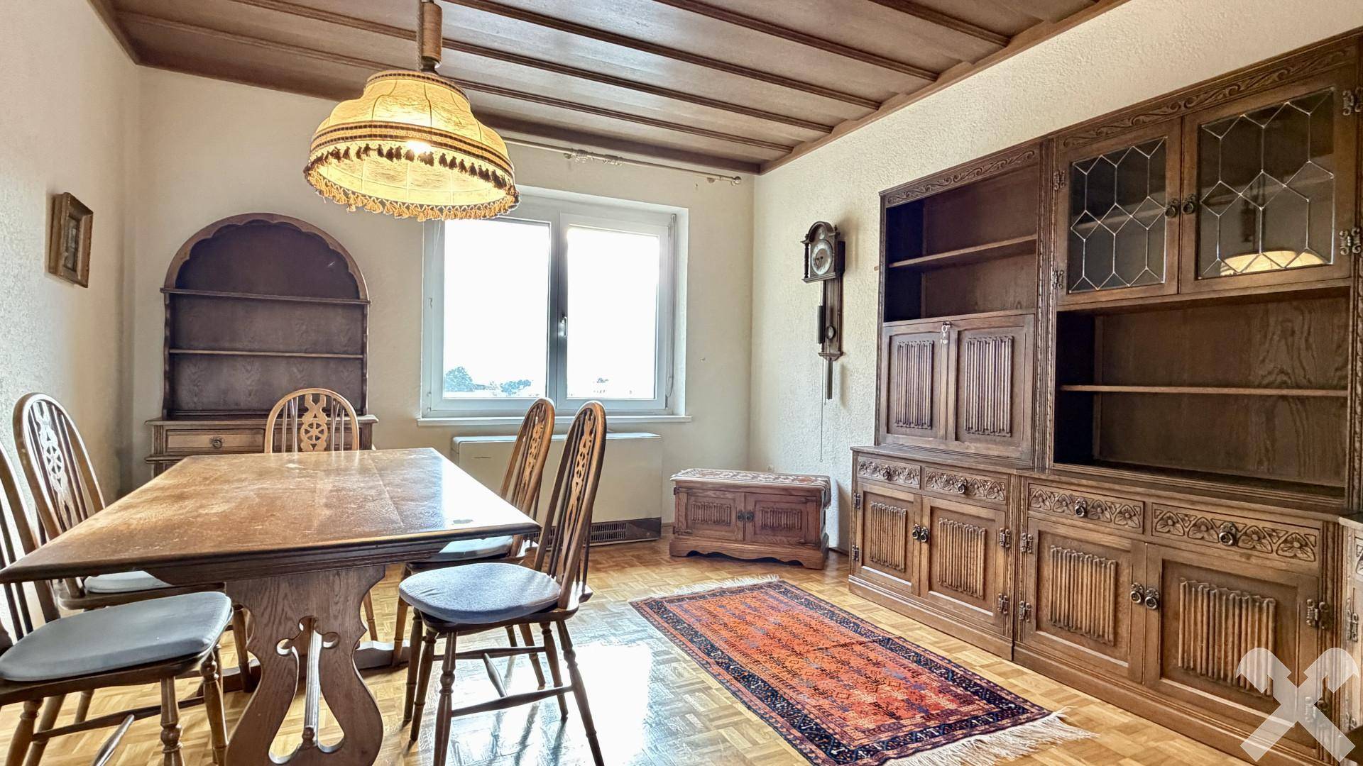 Esszimmer mit rustikalen Holzmöbeln, Parkettboden und einem Fenster mit Ausblick.