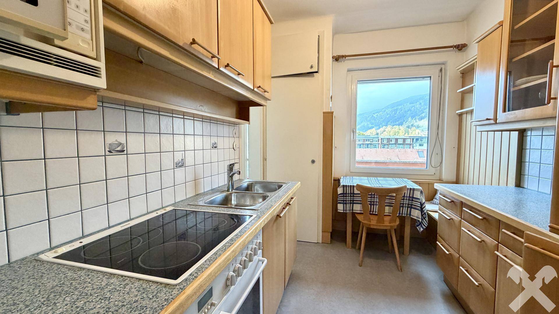 Funktionale Küche mit Einbauschränken, Fliesenrückwand und Essbereich am Fenster.
