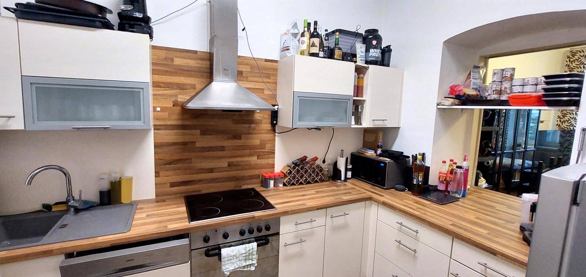 Funktionale Küche mit Holzoptik-Arbeitsplatten, Edelstahlgeräten und Stauraum.