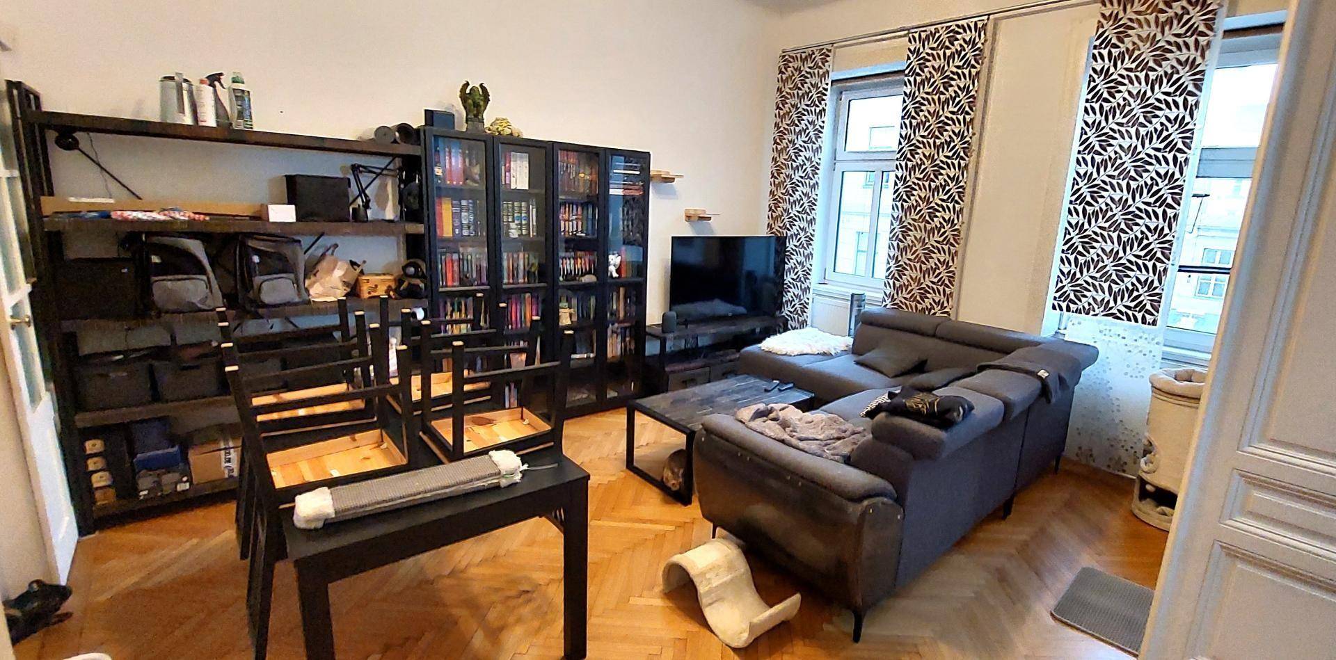 Gemütliches Wohnzimmer mit großem Sofa, Bücherregalen und Parkettboden.