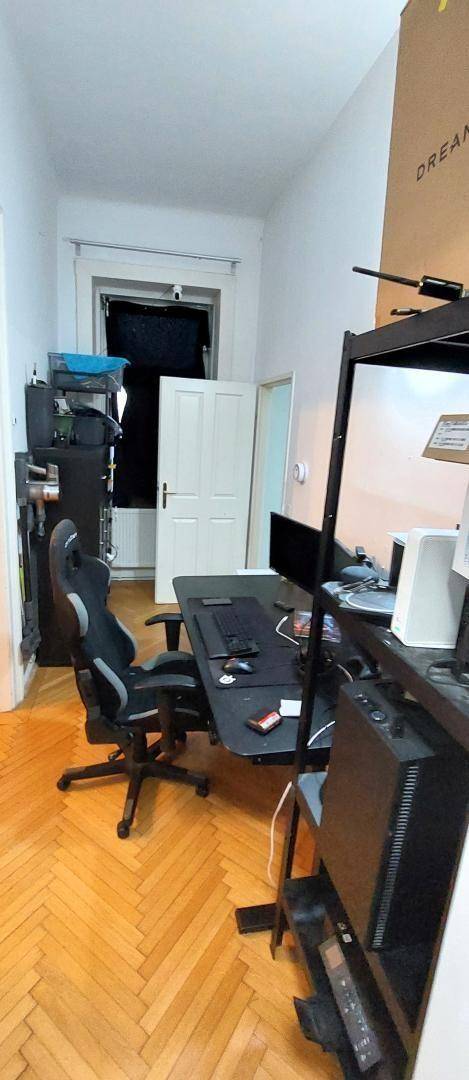 Arbeitszimmer mit Schreibtisch, Gaming-Stuhl und Regalen, ausgestattet für Computerarbeit.