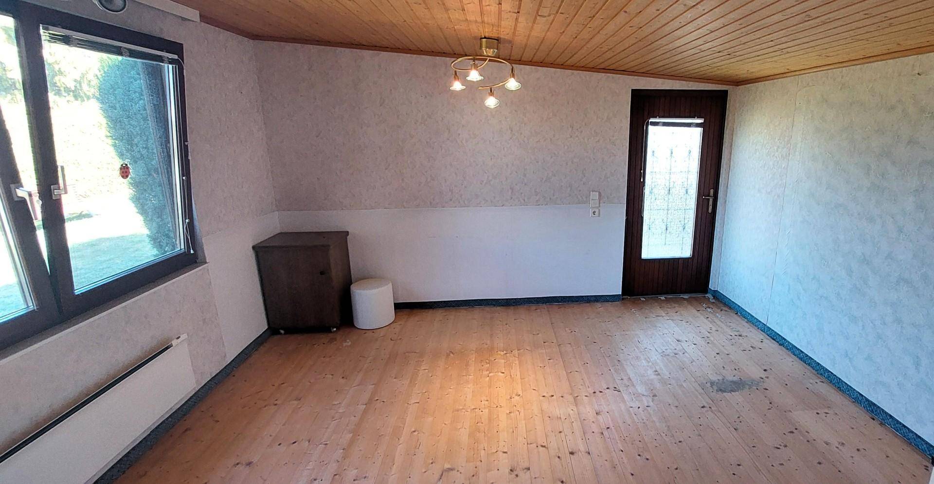Heller Raum mit Holzdecke, Parkettboden und Tapeten, bereit zur individuellen Gestaltung.